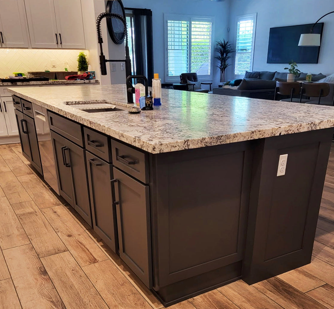 Kitchen island with dark paneled cabinets and a stone countertop by Gentry Stinson