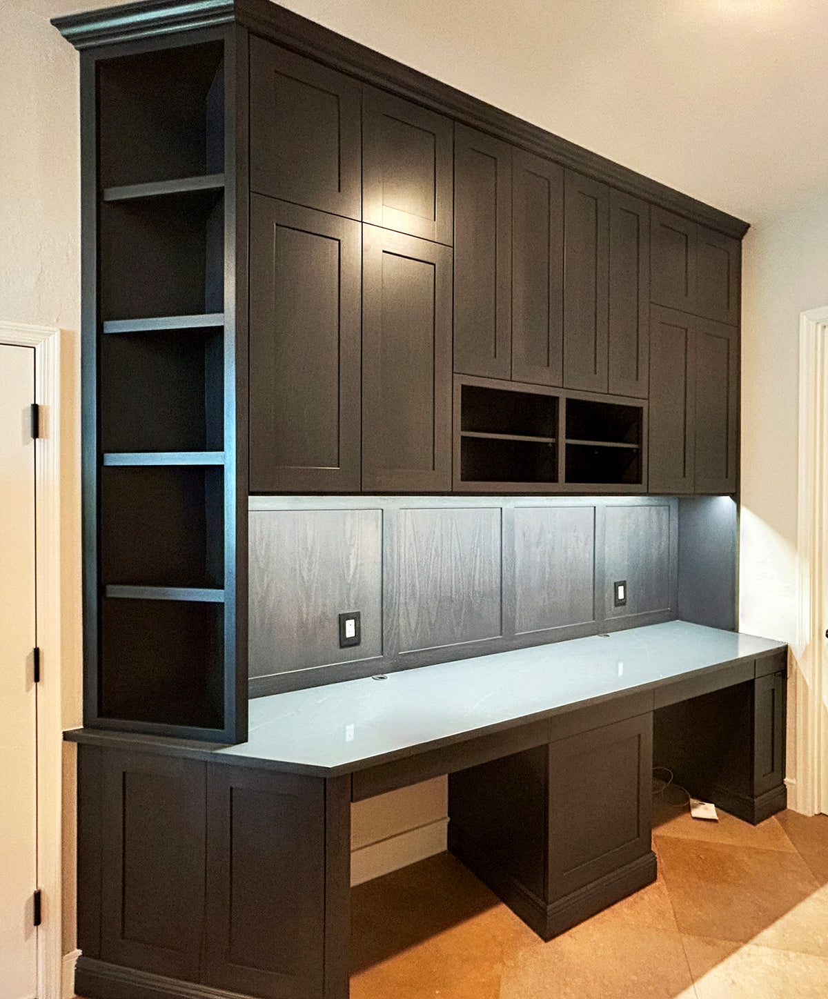 Built-in desk with dark upper storage cabinets, open shelving and task lighting by Gentry Stinson