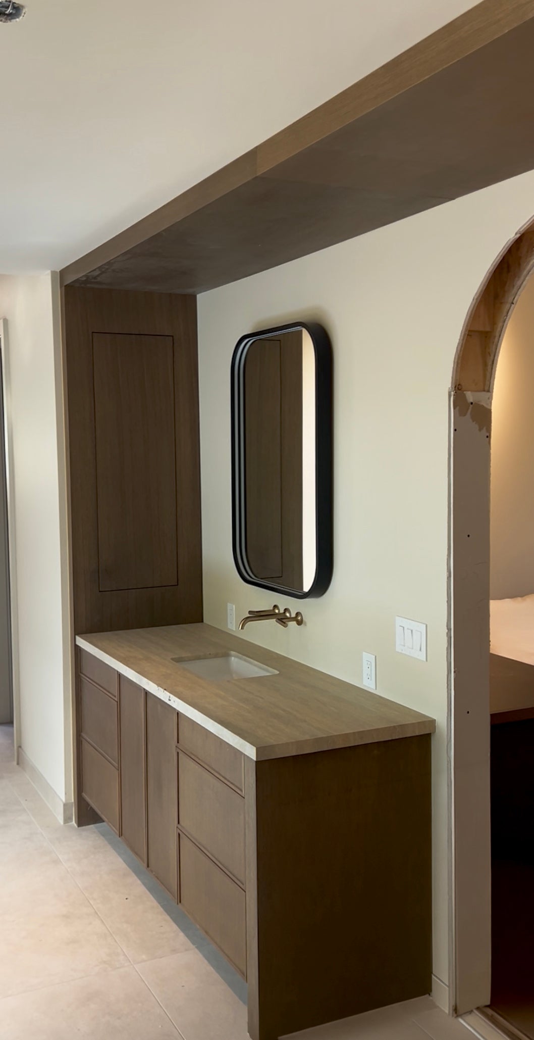 Wood bathroom vanity with an inset sink and wall-mounted mirror by Gentry Stinson