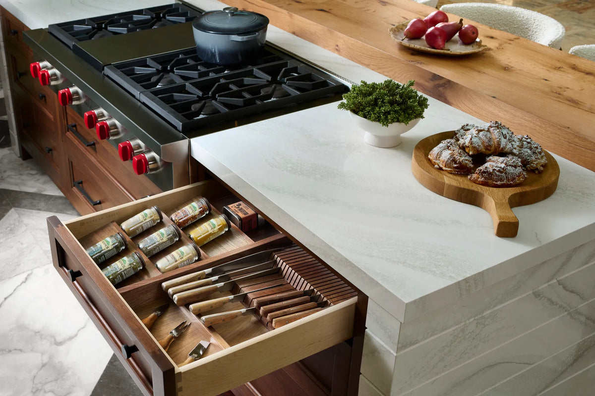 Open kitchen drawer with divided storage for knives, utensils and spice jars