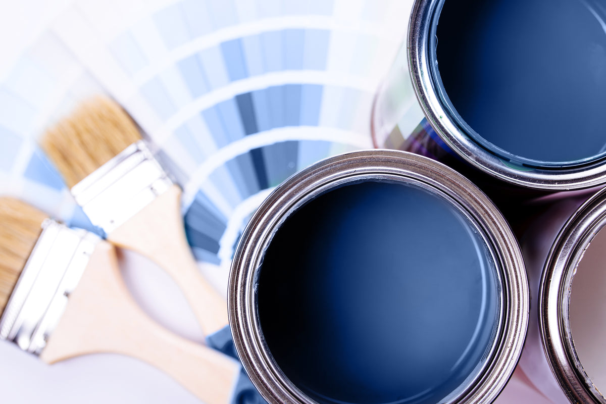 Blue paint cans, a paintbrush and color samples for cabinet finishes