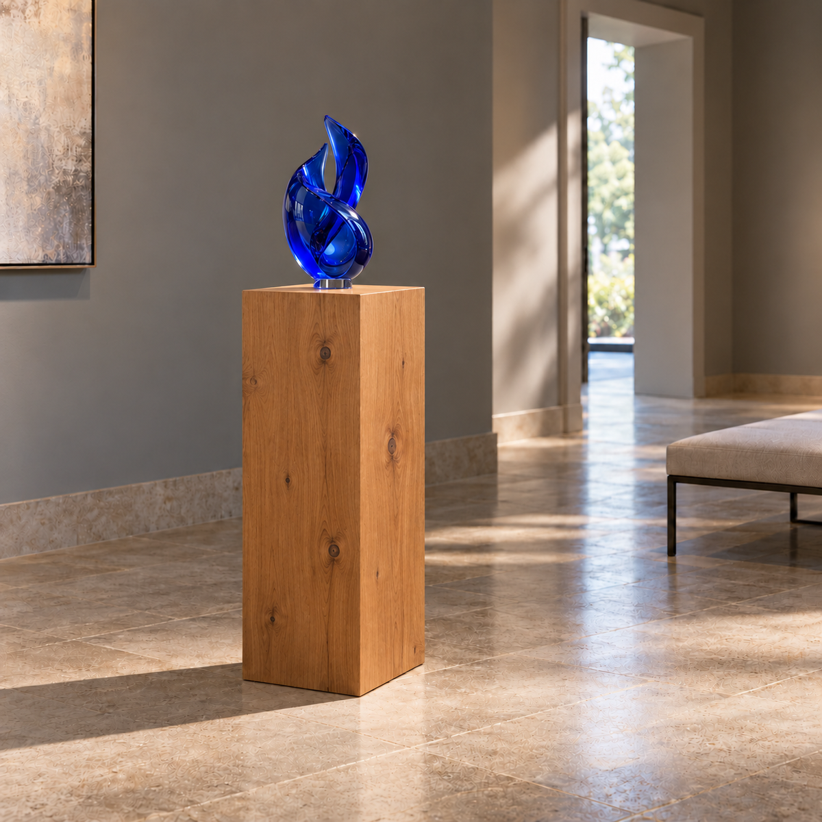 Titan Knotty Alder display pedestal, 12 × 16 × 30 inches, Rubio Monocoat Bourbon, in a glass-gallery setting. Illustrative room scene; artwork not included.