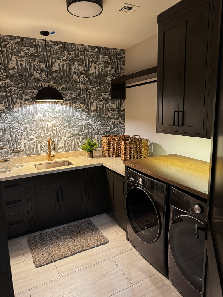 Custom black laundry room cabinetry with wallpaper and brass accents